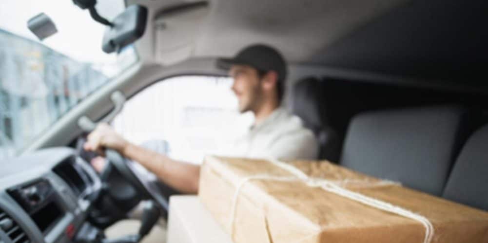 Motorista em seu veículo levando encomendas até o local de entrega