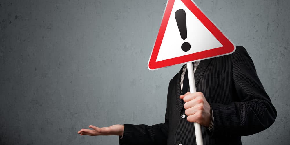 Homem com terno segurando uma placa com um ponto de exclamação desenhado