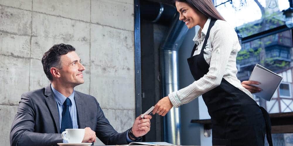 Trabalhador vestindo terno pagando seu almoço no restaurante com vale-refeição