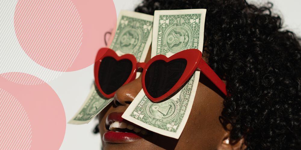 Mulher negra vestindo óculos com lentes em formato de coração com notas de dinheiros presas às lentes