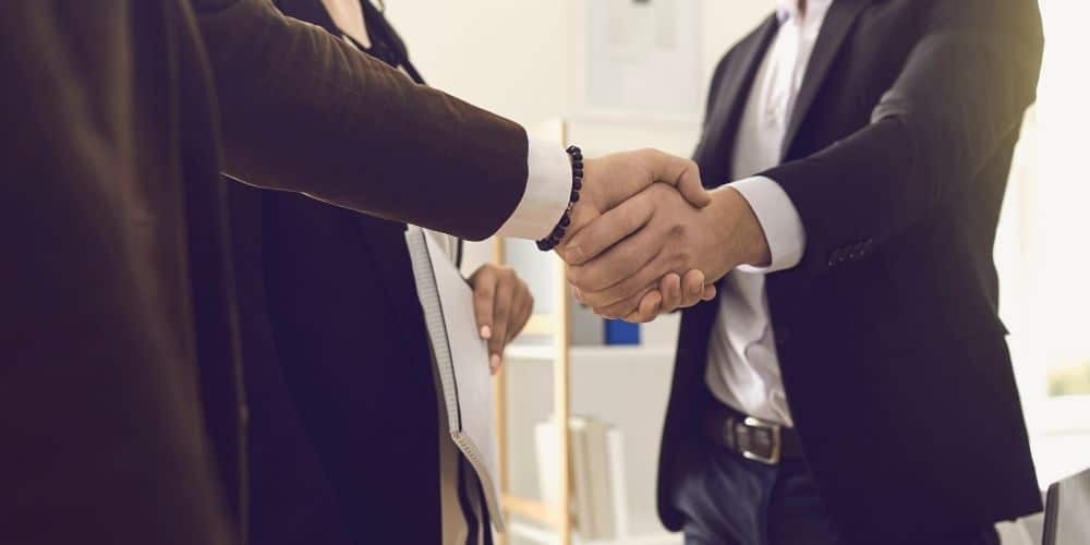 Pessoas de trajes sociais de trabalho apertando as mãos