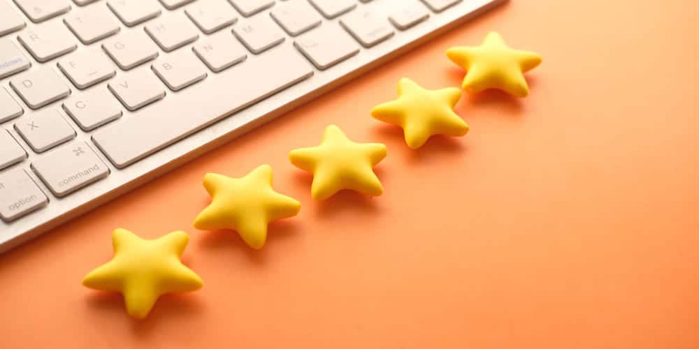 Fileira de estrelas amarelas feitas de plástico em frente a um teclado branco em mesa de tampo laranja