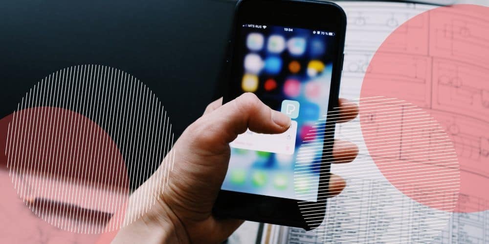 Smartphone sendo segurado por uma mão cujo dedão clica em um aplicativo