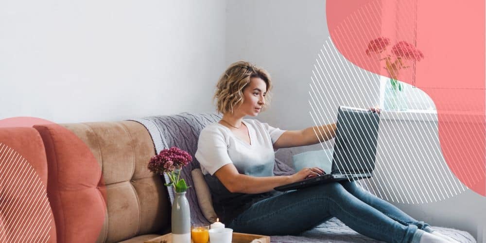 Mulher loira de cabelos curtos trabalhando no modelo de home office no sofá de sua casa com um laptop no colo