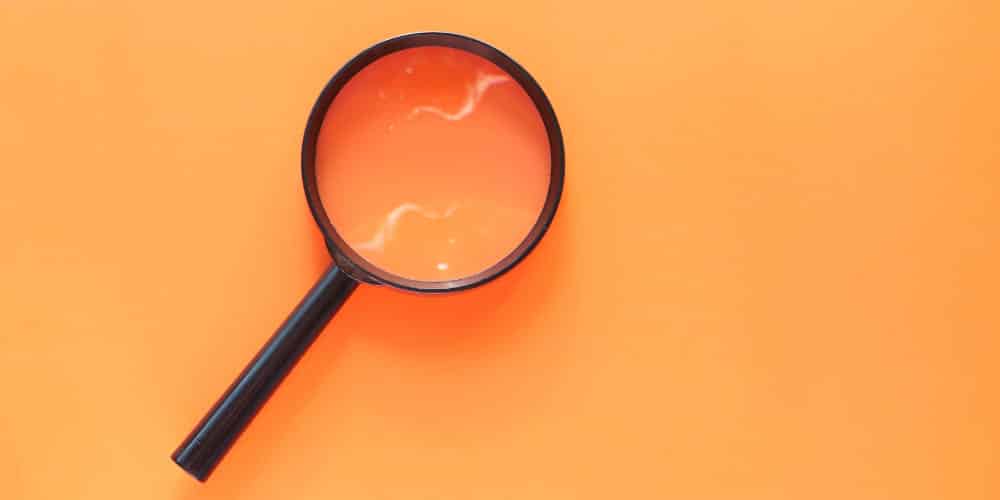 Lente de aumento preto apoiada sobre fundo laranja