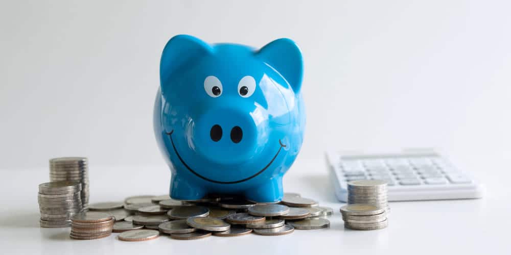 Cofre em formato de porquinho sorridente com moedas prateadas ao redor dele