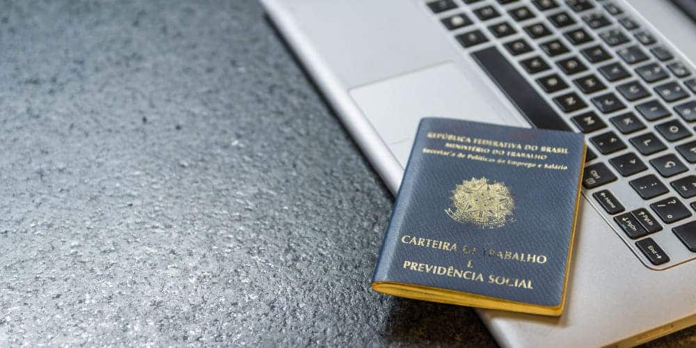 Carteira de trabalho do Brasil sobre laptop prateado aberto em mesa de trabalho