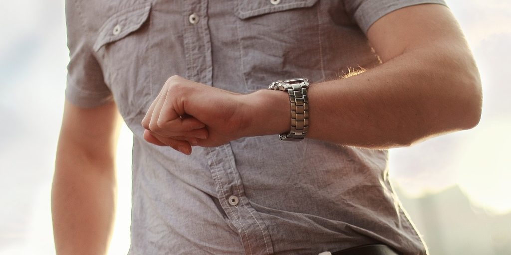 Homem branco checando as horas em seu relógio de pulso.