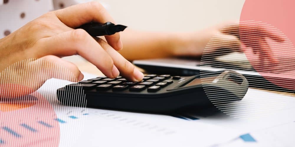 Mãos femininas fazendo cálculos em uma calculadora preta enquanto segura uma caneta preta entre os dedos