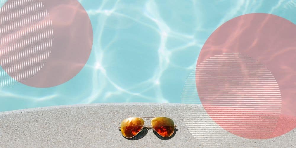 Óculos de sol de lentes laranjas na beirada de uma piscina azul iluminada pelo sol