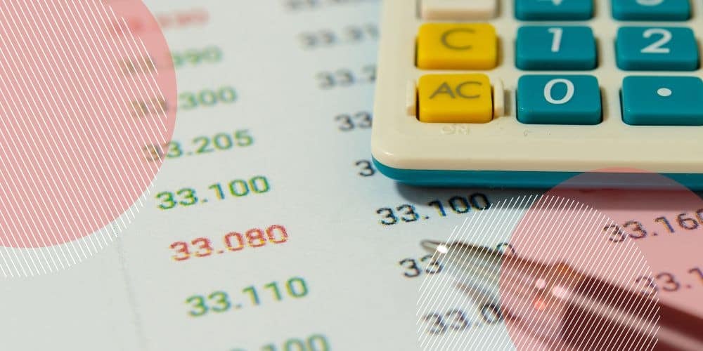 Calculadora apoiada sobre folha de contabilidade que apresenta números impressos em verde e em vermelho