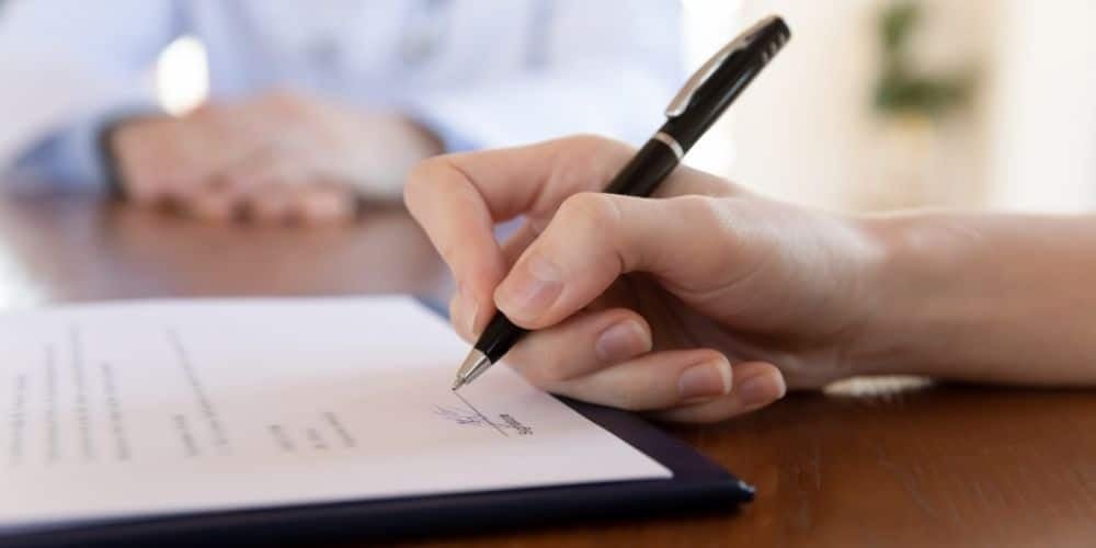 Mão assinando contrato social com uma caneta preta