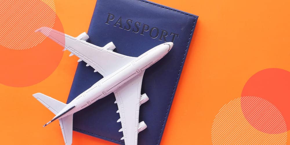 Avião de brinquedo branco sobre passaporte azul em fundo laranja