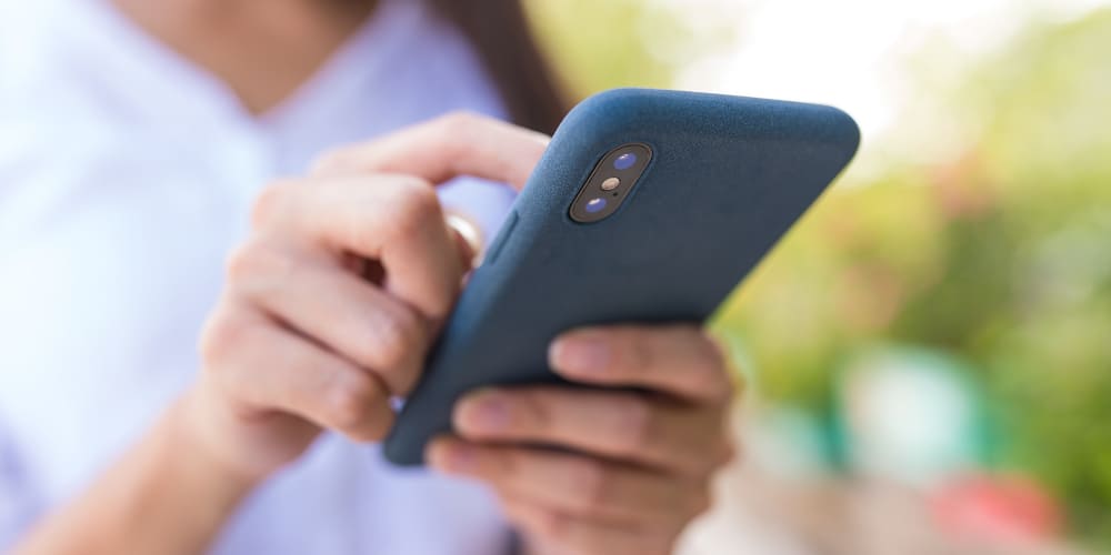 Mulher manuseando seu smartphone para fazer seu controle de ponto por aplicativo