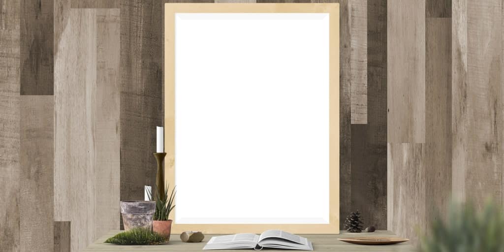 Moldura de espelho apoiada sobre mesa de escritório e contra uma parede de madeira