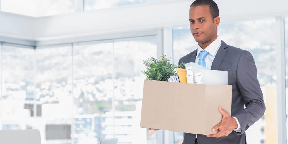 Homem carregando seus itens de trabalho em caixa de papelão para sair do escritório