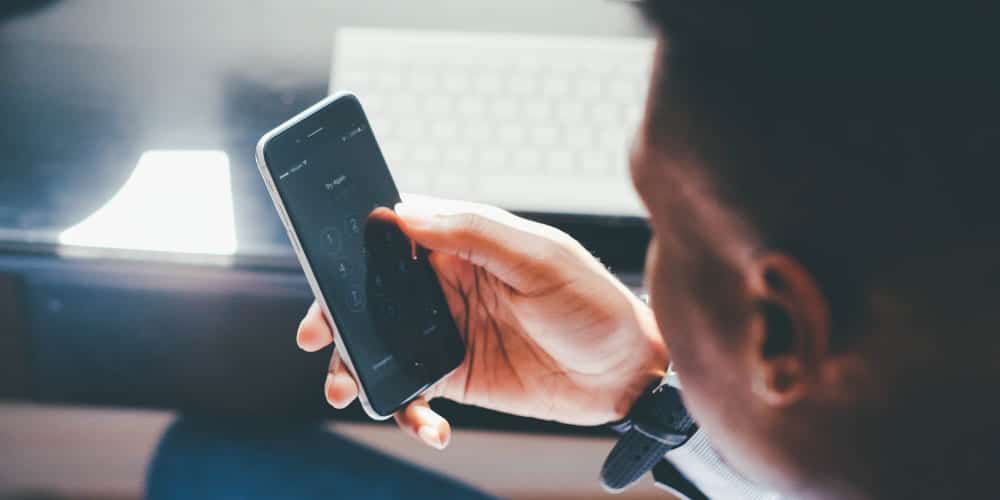 Homem segurando seu smartphone para fazer seu registro de ponto em seu marcador de ponto digital