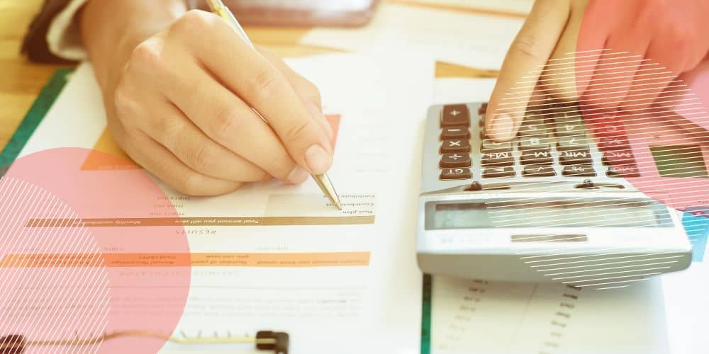 par de mãos escrevendo em um holerite e fazendo contas em uma calculadora