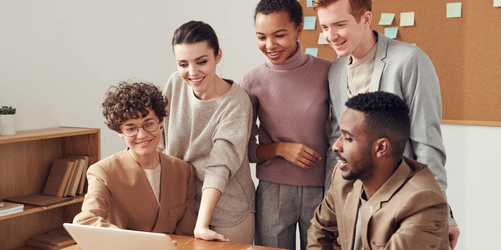 Grupo de cinco colegas de trabalho vendo informações de onboarding em tela de computador