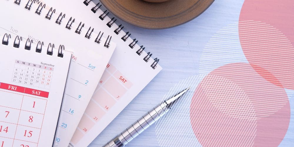 conjunto de calendários de mesa coloridos sobrepostos no canto esquerdo da foto, sobre uma mesa de madeira