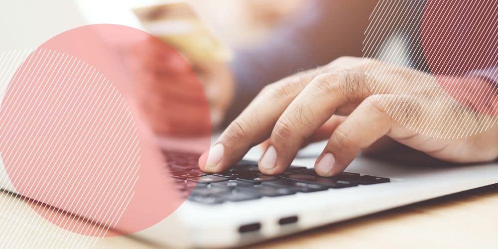 Mão masculina em foco principal enquanto mexe nos teclados de um computador para fazer seu controle de ponto online gratuito