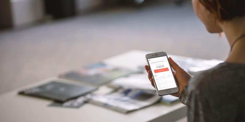 Mulher segura seu smartphone aberto no aplicativo de controle de ponto da mywork para bater seu ponto pelo celular