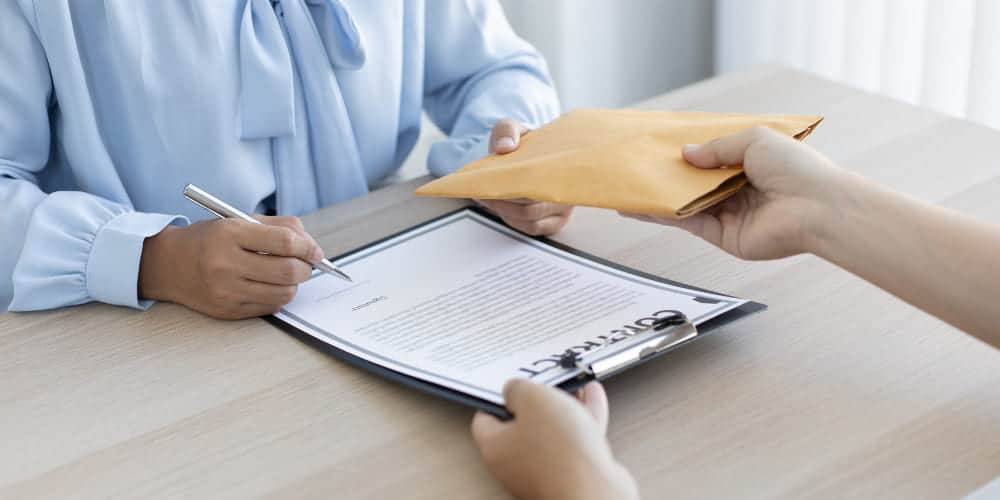 Pessoa assinando documento preso em prancheta para receber sua remuneração variável em envelope bege