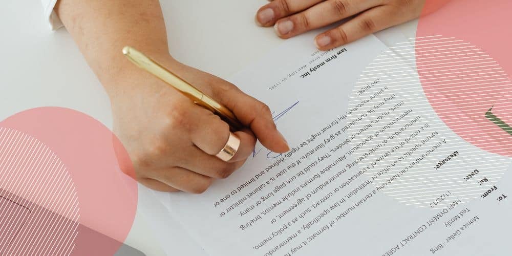 mão feminina adornada com anel dourado no dedo indicador direito assina documento com uma caneta dourada