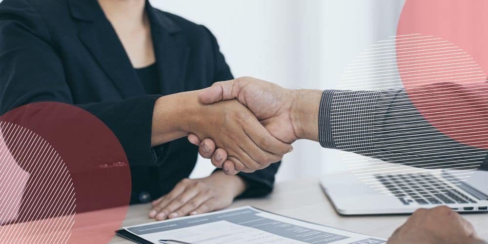 Foto de mulheres apertando as mãos sobre mesa de trabalho em escritório