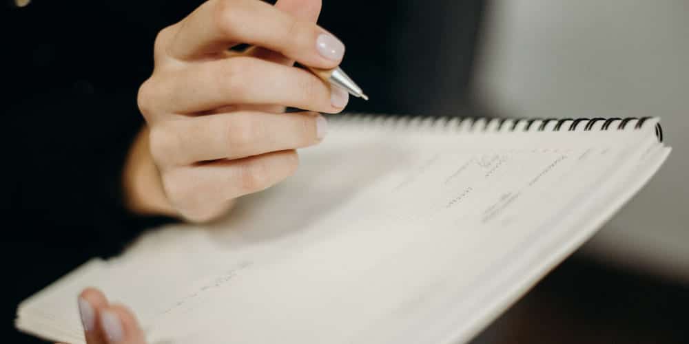 Imagem de mãos segurando documento e uma caneta prateada para assinatura
