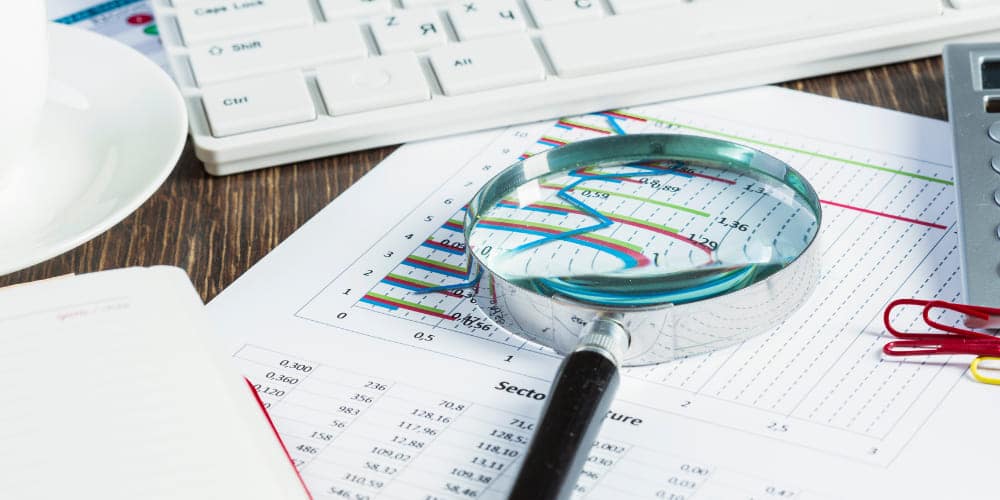 Lente de aumento sobre documentos que mostram gráficos de rotatividade de funcionários