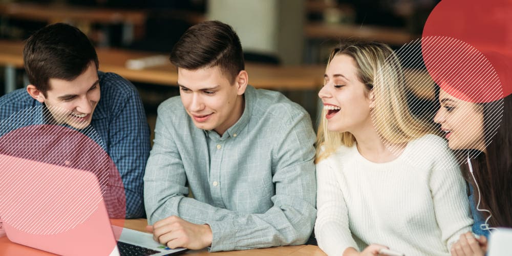 Trio de estagiários conversando em mesa de trabalho em escritório