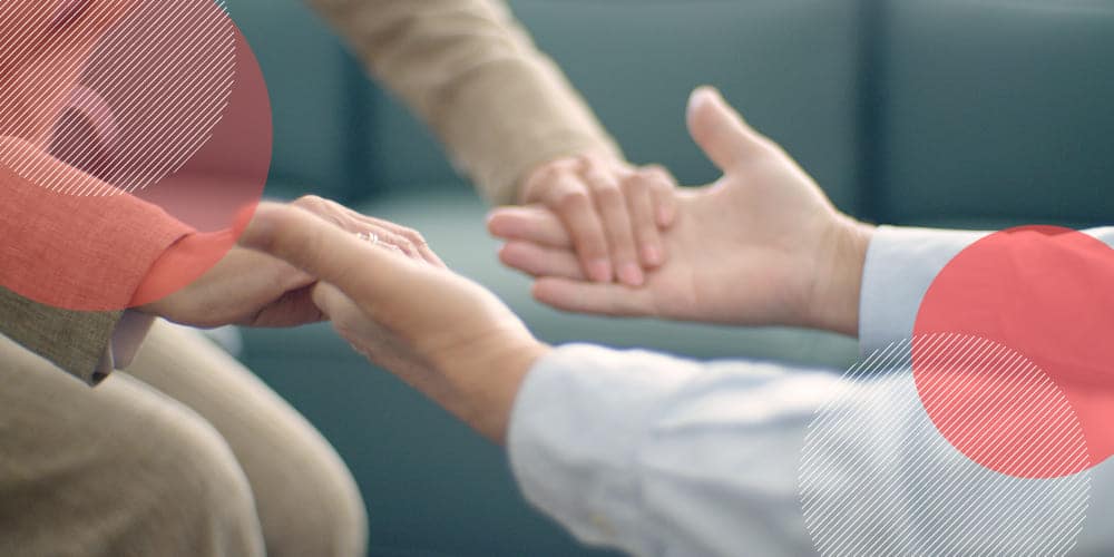Pessoas sentadas de frente uma para a outra segurando as mãos