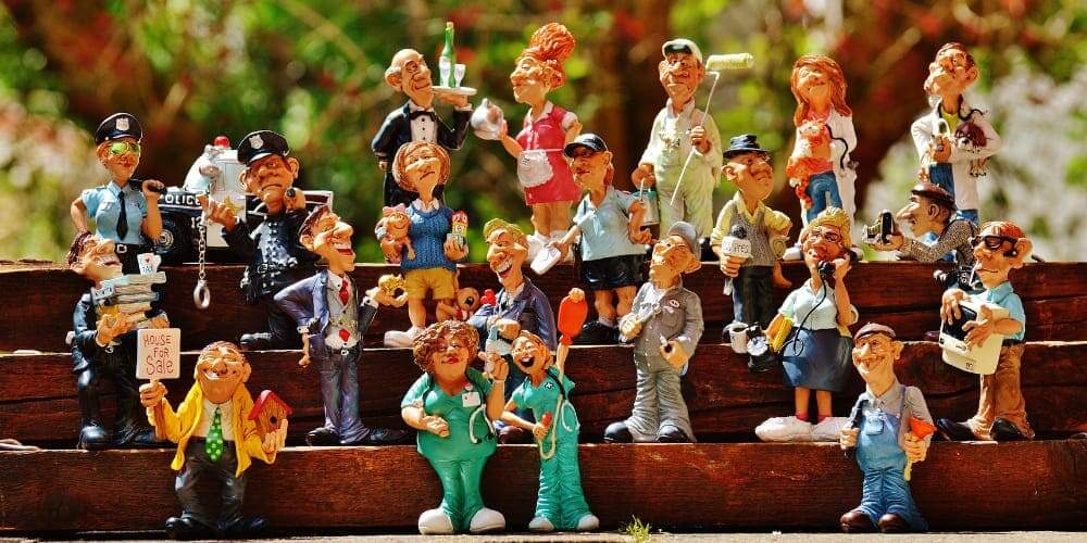 Imagem de miniaturas de diferentes profissionais organizados em uma prateleira em frente a fundo de janela