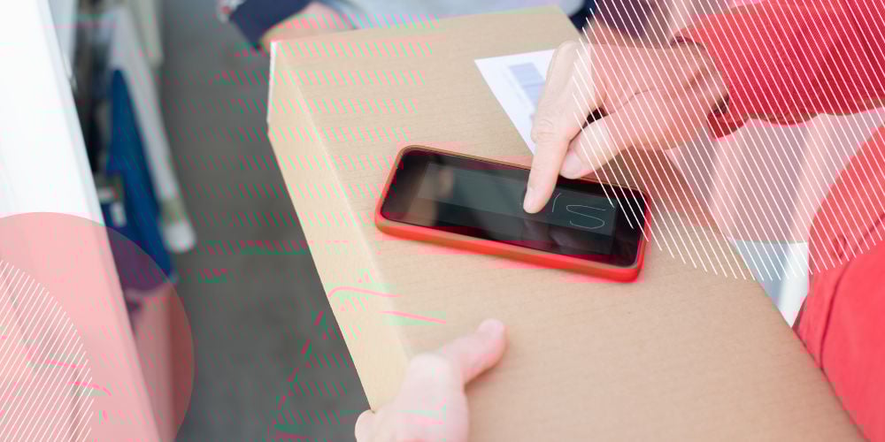 Pessoa assinando documento pelo celular enquanto segura uma caixa de papelão