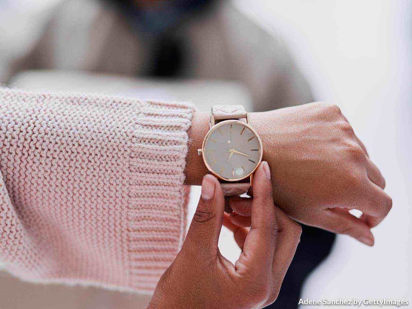 Close up em um relógio de pulso usado por uma mulher que segura o aro do relógio para ver as horas