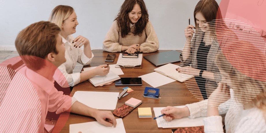 grupo de jovens trabalhando alegremente sobre uma mesa compartilhada feita de madeira