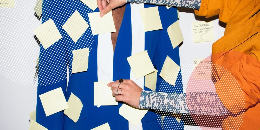 Pessoa vestida com blazer azul bic com vários post-its amarelos colados no tecido