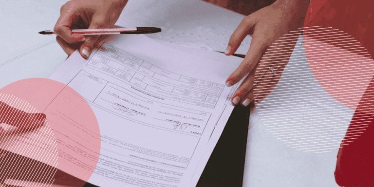 mão feminina segurando documentos e uma caneta preta entre os dedos