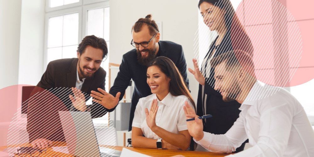 Cinco colegas de trabalho reunidos ao redor de um laptop em escritório