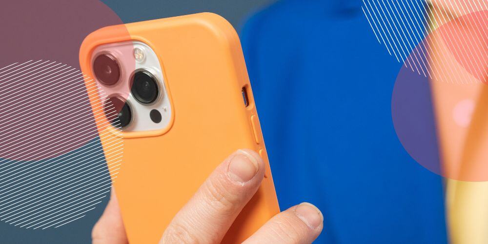 Celular com capinha laranja sendo segurado em frente à câmera