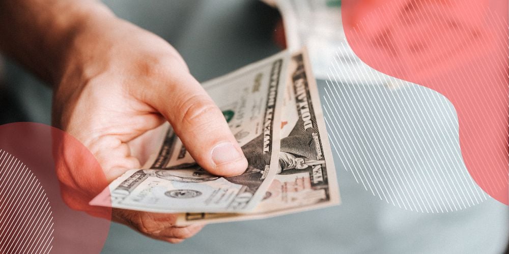 Mão masculina segurando notas de dinheiro em frente à câmera